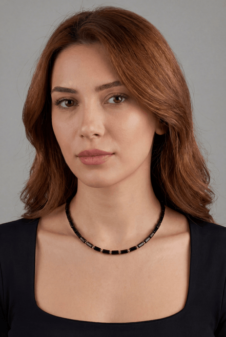 Woman wearing a black beaded necklace against a gray background